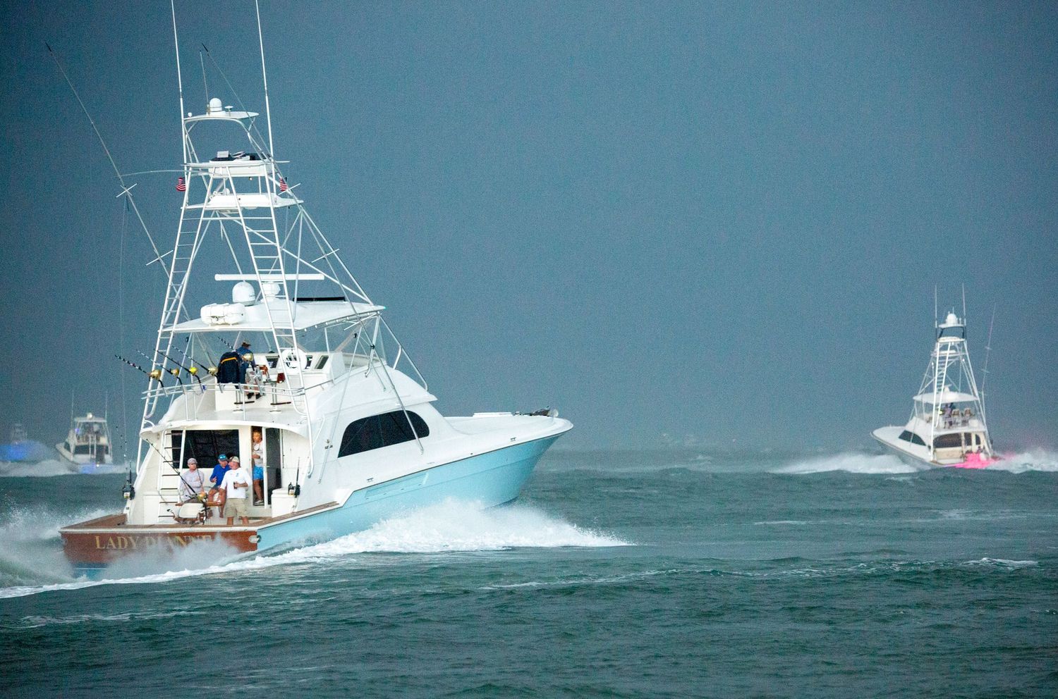 Luxury fishing boats cruise through dark stormy waters during rough weather conditions.