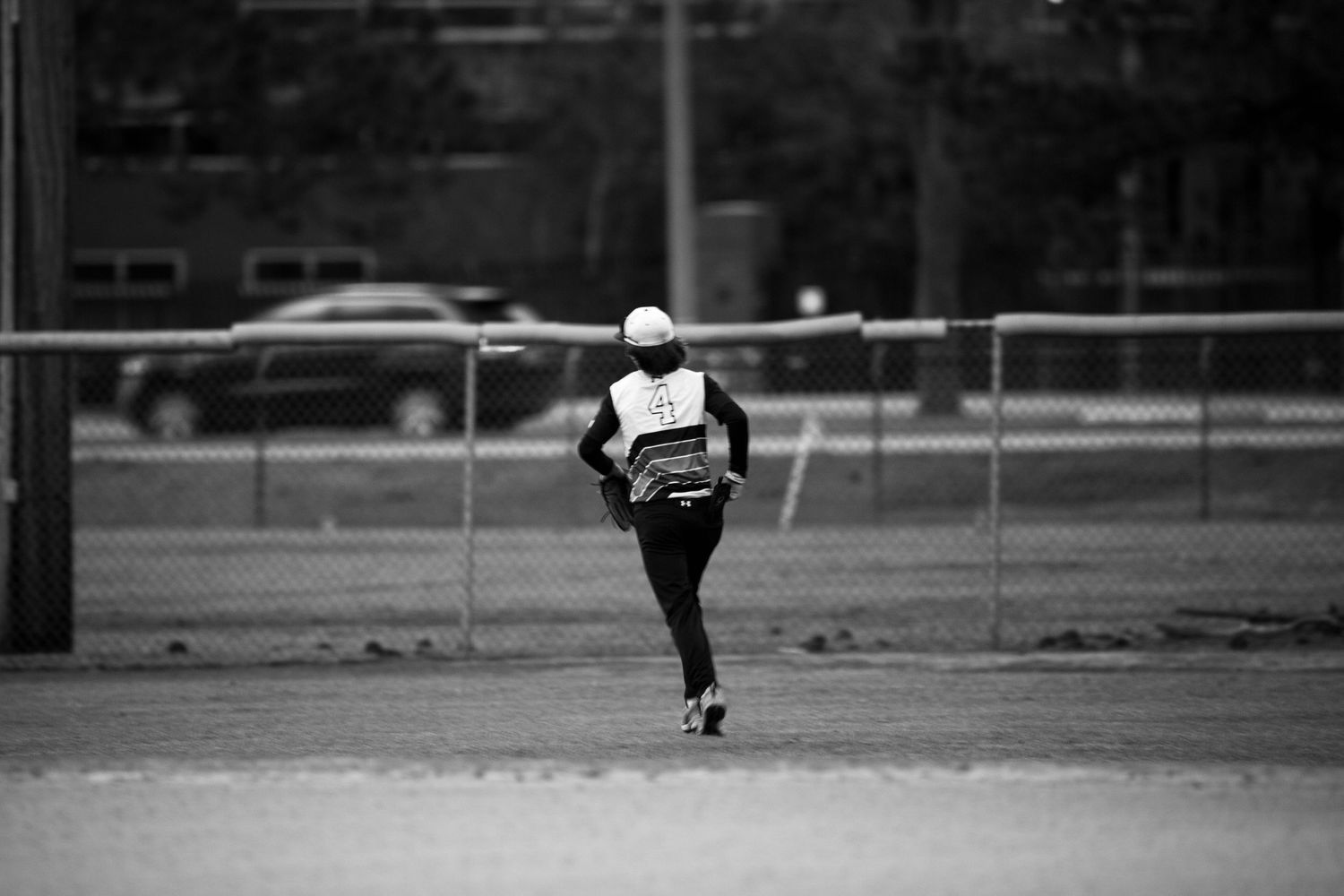 Black and white photo of Baseball player running on empty field.