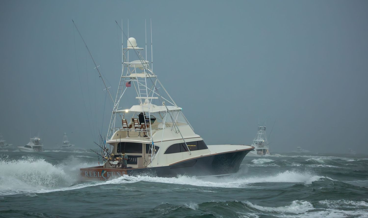 Sport fishing boats powering through rough ocean swells in overcast conditions.
