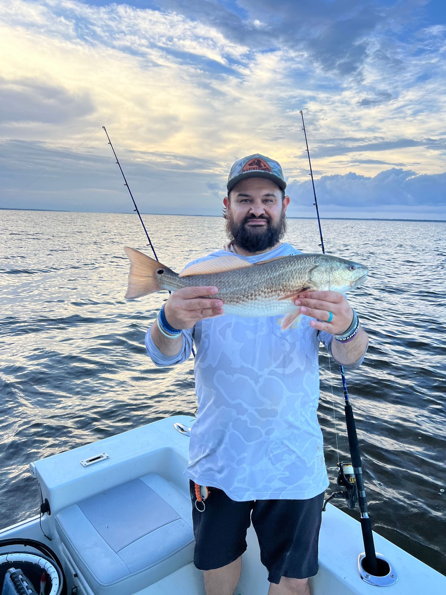 Five sequential photos showing a successful redfish catch from boat on calm ocean waters at sunset.