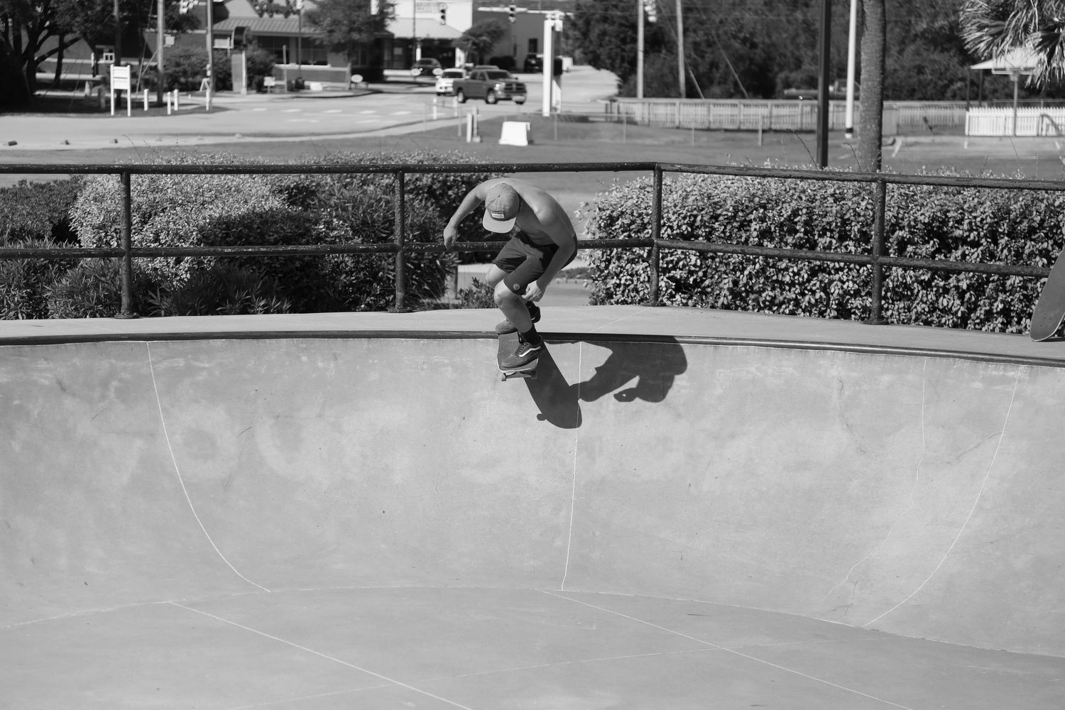 A skateboarder performs a trick in a concrete skate park bowl captured in black and white photography.