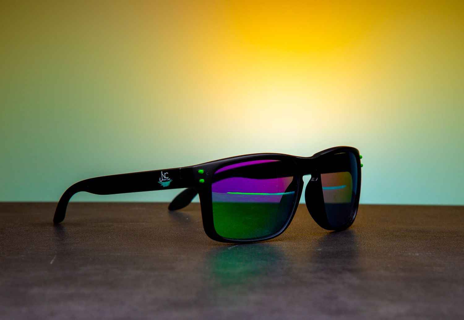 Black sunglasses with reflective lenses displayed against colorful gradient background.