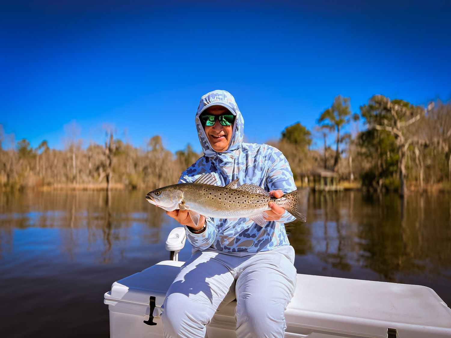 Multiple fishing shots taken on a lake with bright blue skies and cypress trees in the background.