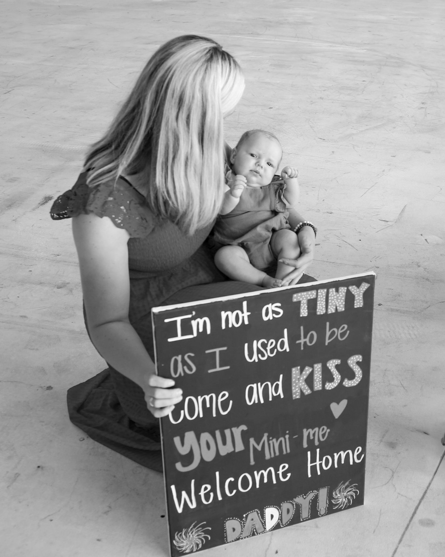 A series of black chalkboard signs showing a welcome home message being photographed in different poses on a wooden floor.