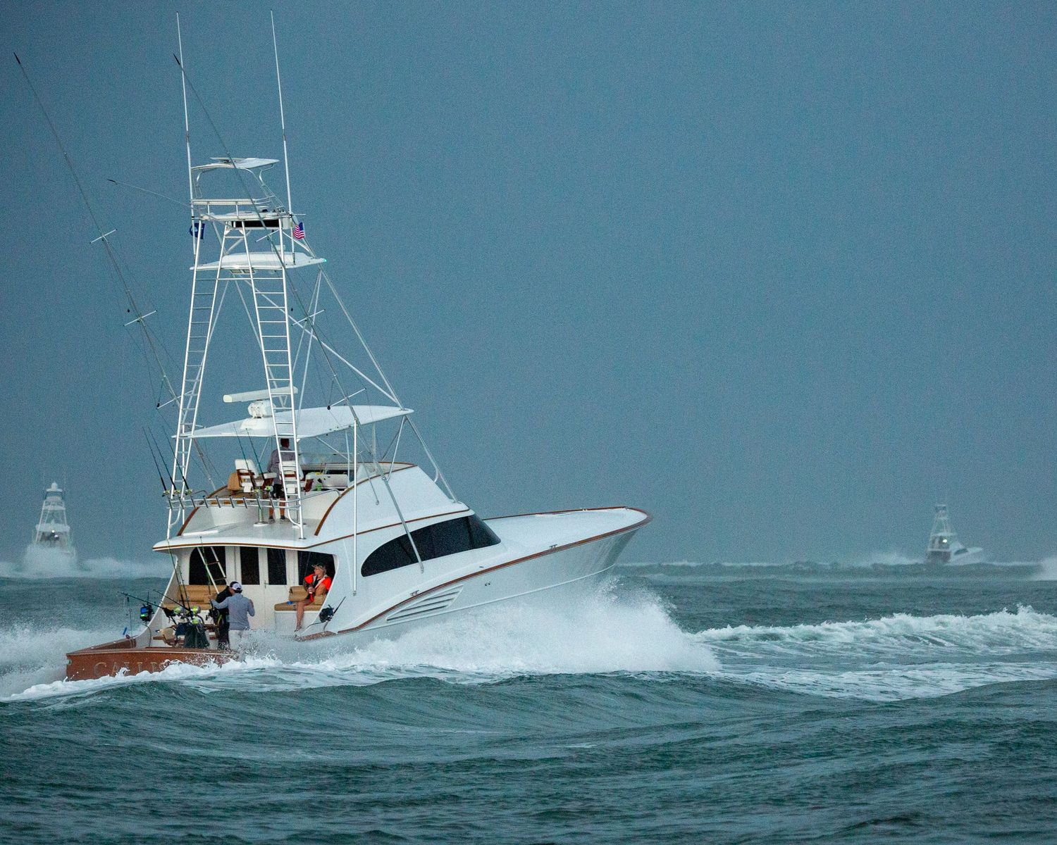 Sport fishing boats navigate through choppy waters on a stormy day.