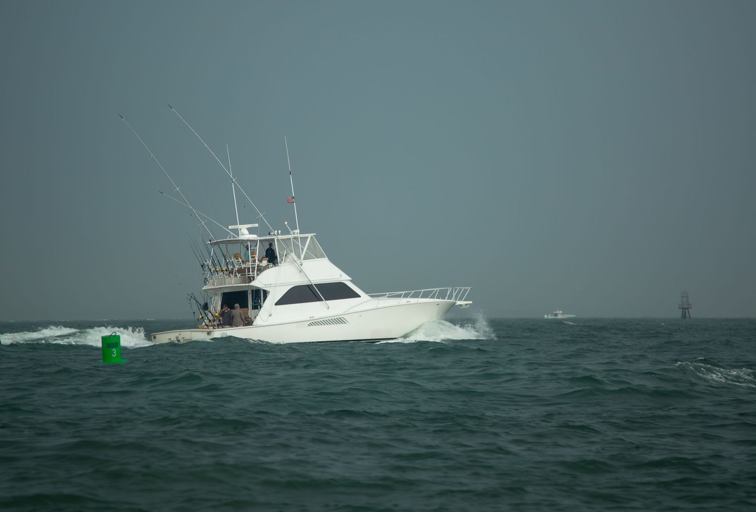 Sport fishing vessel moving through calm waters with navigation markers visible.