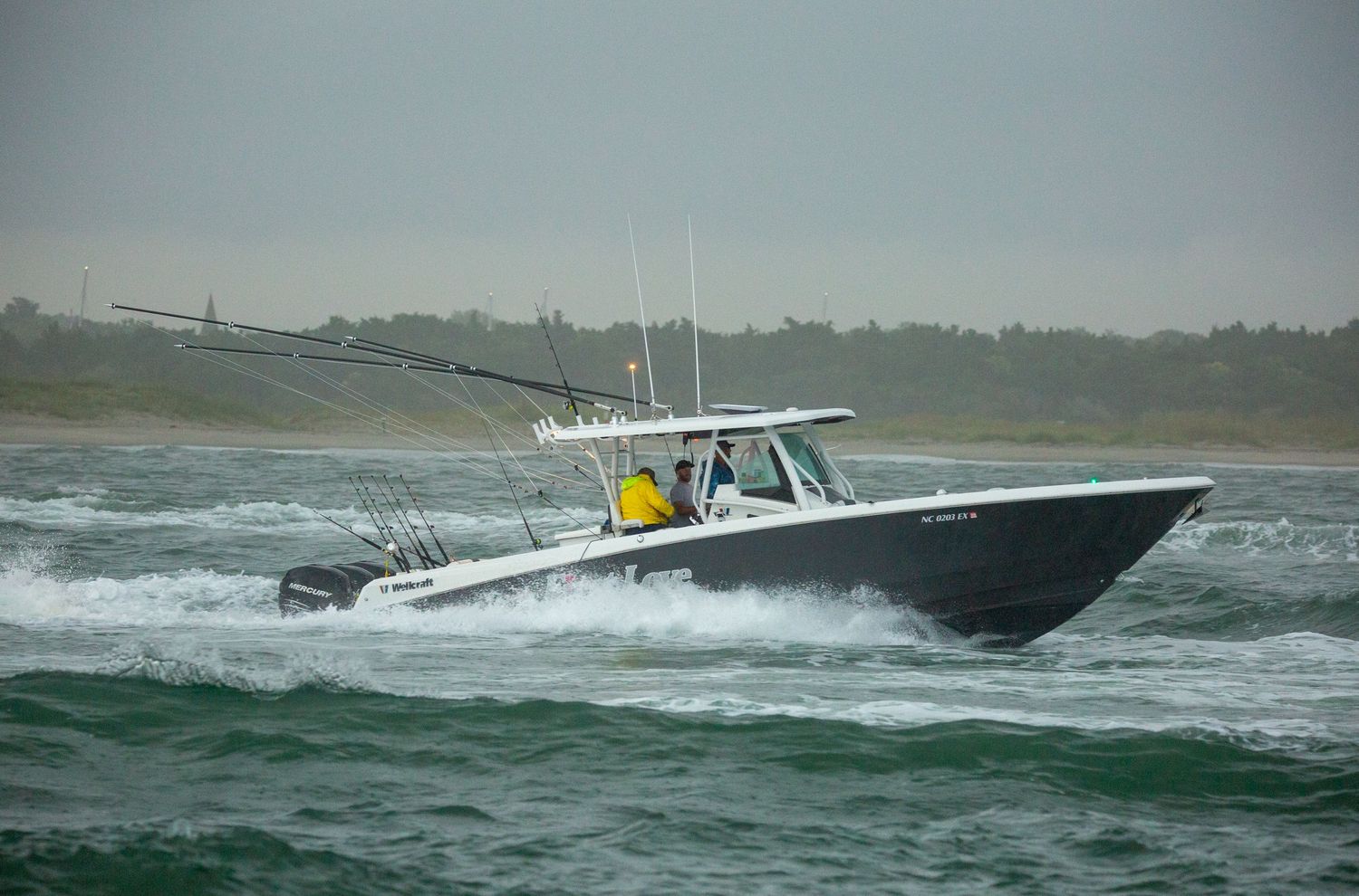 Large center console fishing boat cutting through rough ocean waves.