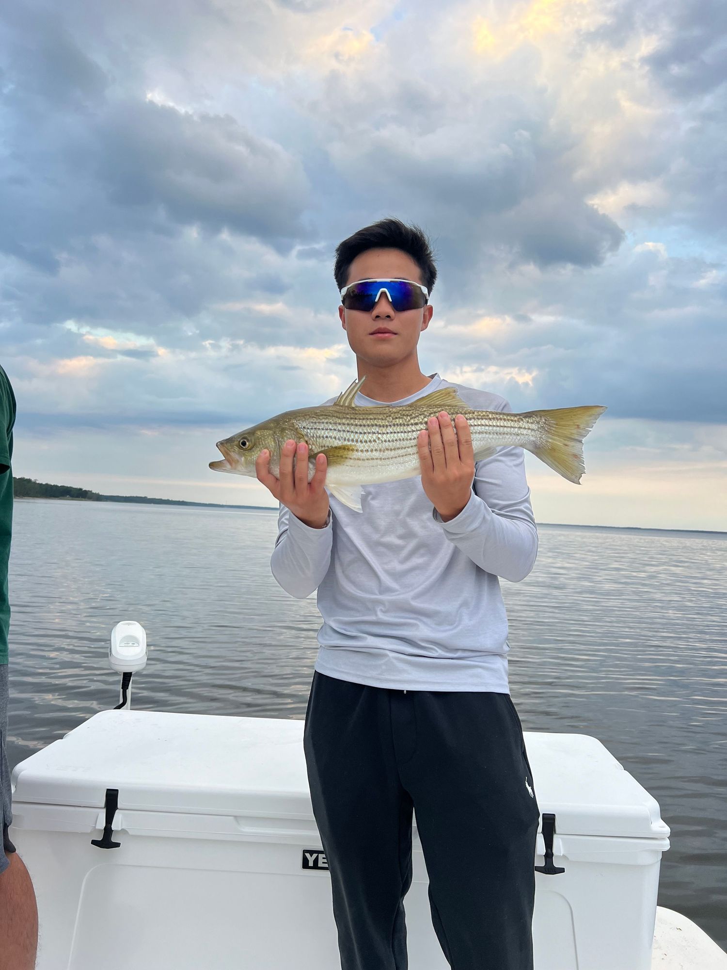 Young angler shows off snook catch during cloudy evening on boat.