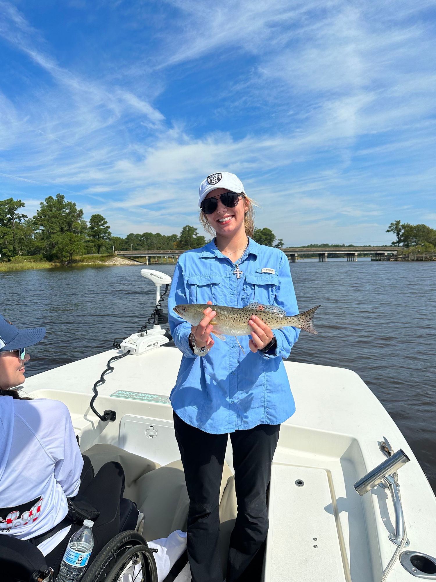 Fishing boat trip participants showing off their catches with blue skies in the background.