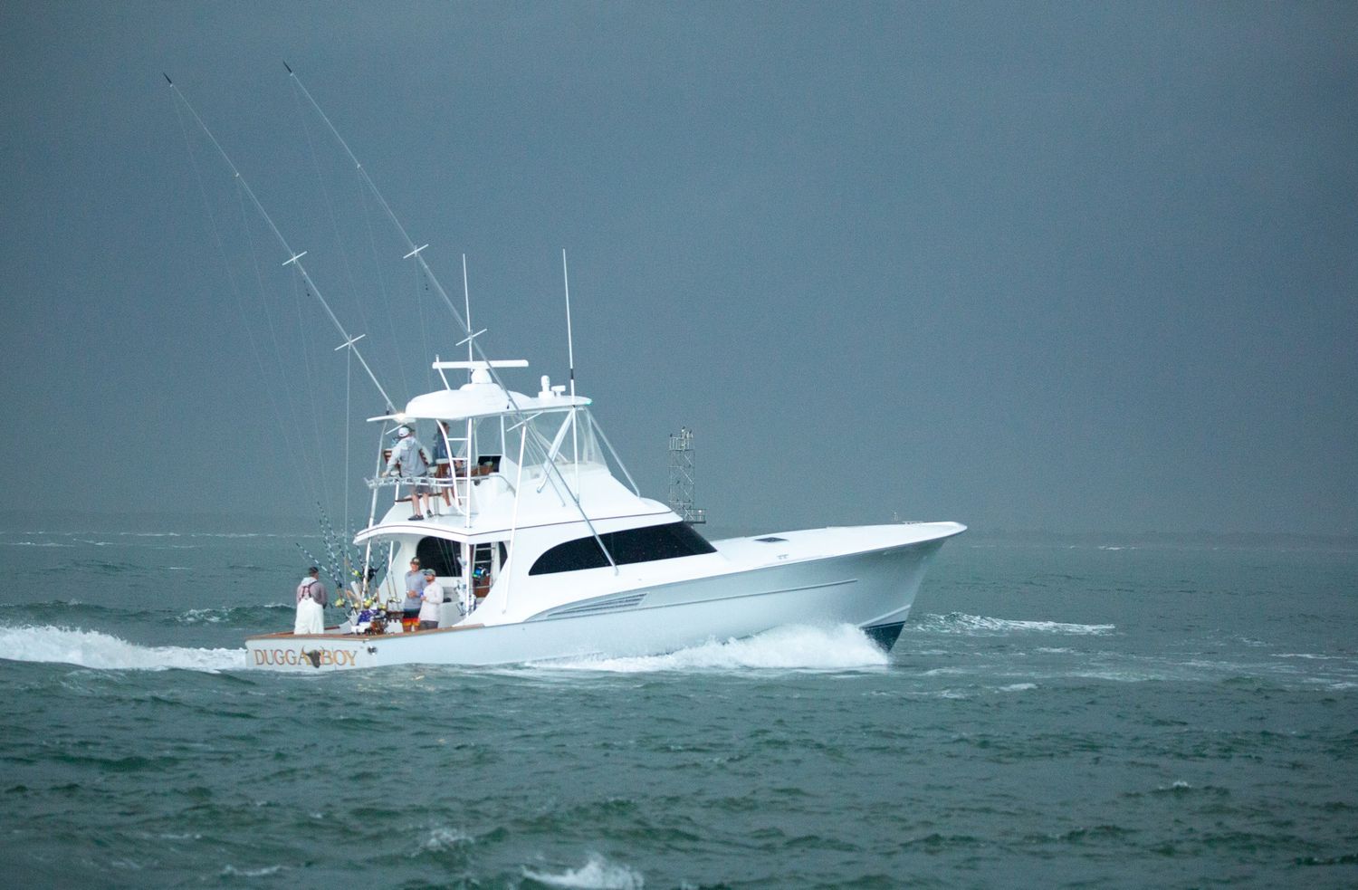 White sportfishing boat cutting through blue ocean waves on a clear day.