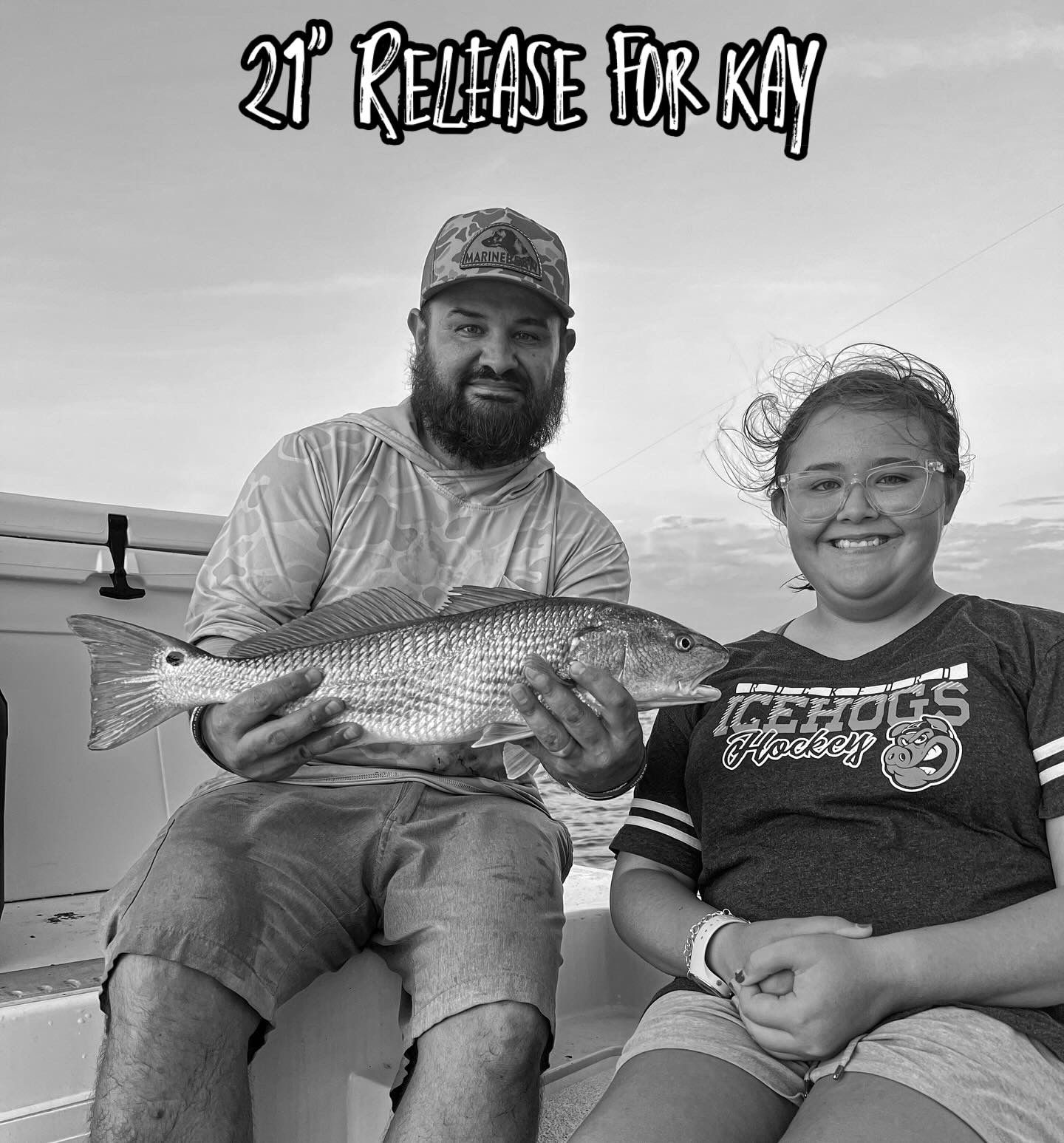 Two anglers display their redfish catch while sitting on a boat during a successful fishing trip.