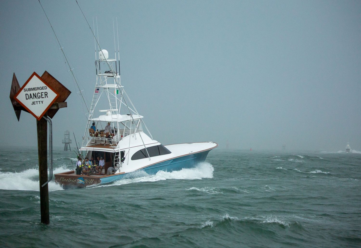 Fishing yacht navigating past a warning sign in stormy weather conditions.