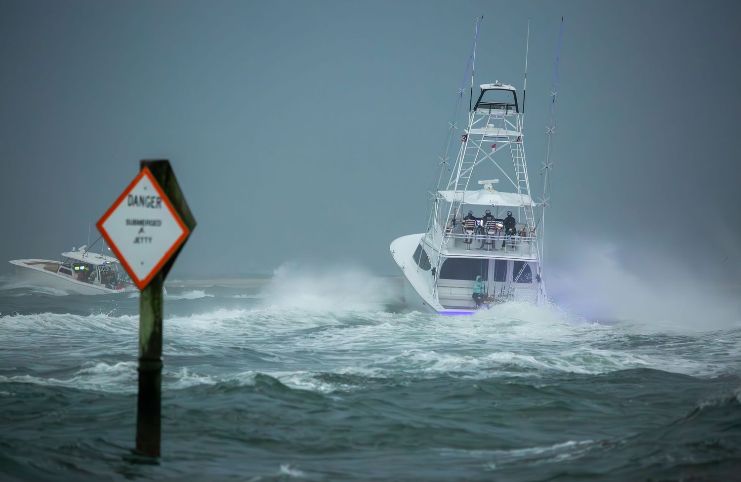 Sport fishing boat navigating through rough ocean waves near a channel marker in stormy conditions.
