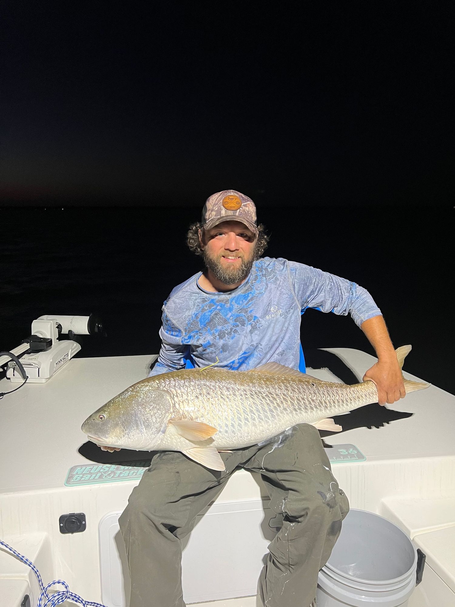 Night fishing success with large redfish caught on deck of boat.