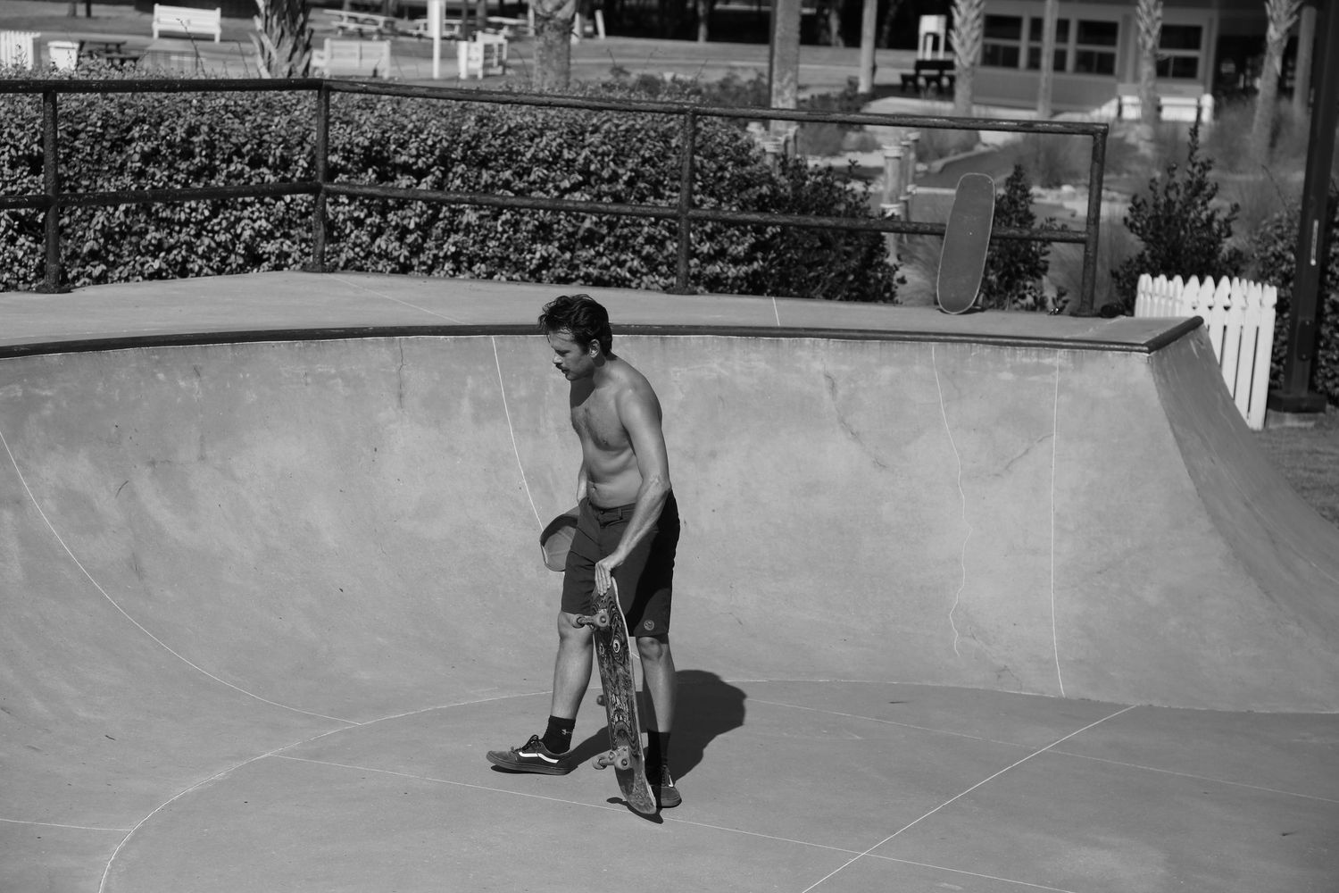 A skateboarder stands in a smooth concrete skate park bowl preparing for a run in black and white.