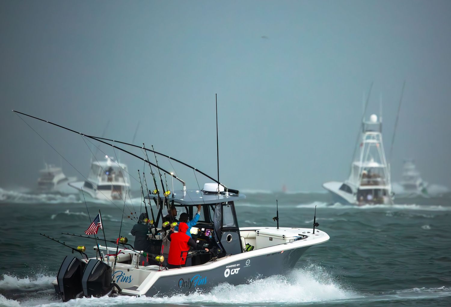 Sport fishing boats navigate through rough ocean waters during stormy conditions.