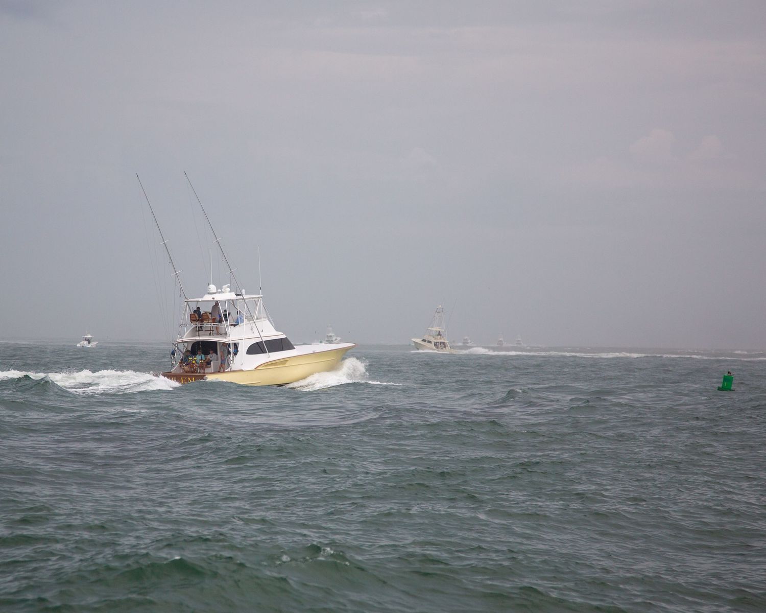Yellow sport fishing boat cutting through choppy waters with other vessels visible in distance.