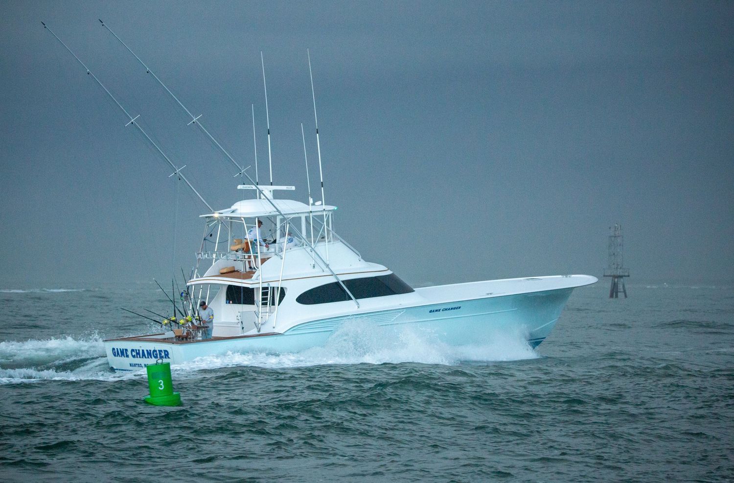 Sport fishing yacht battles rough ocean conditions with green marker visible in background.