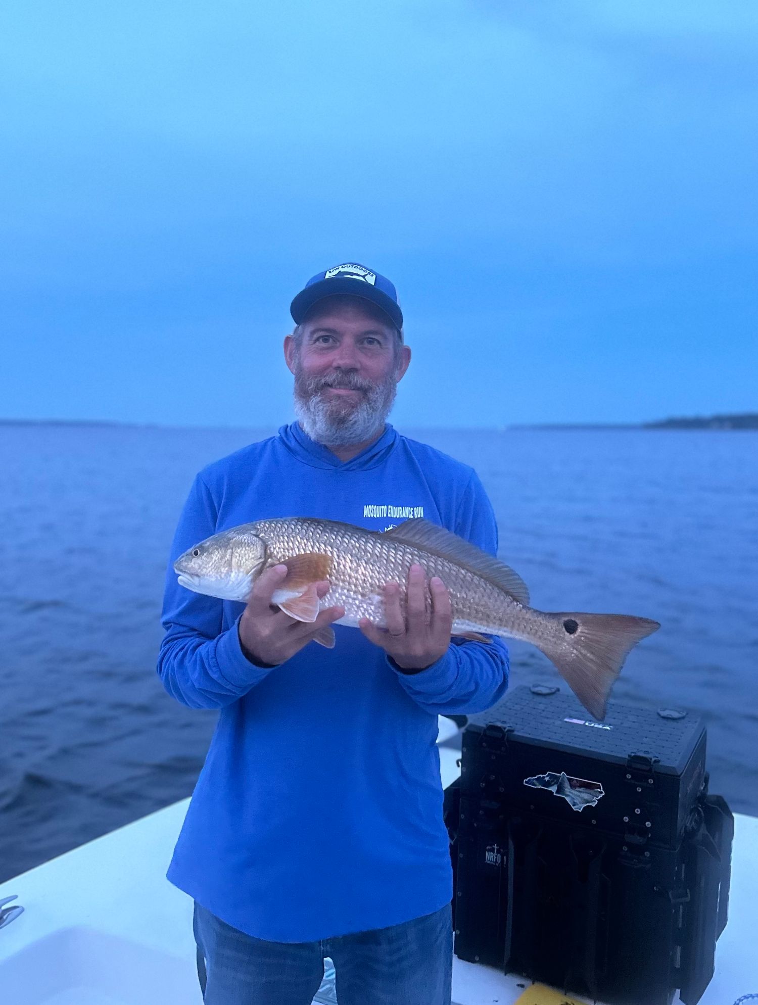 Fresh redfish catch displayed on boat with coastal waters in background at dusk.