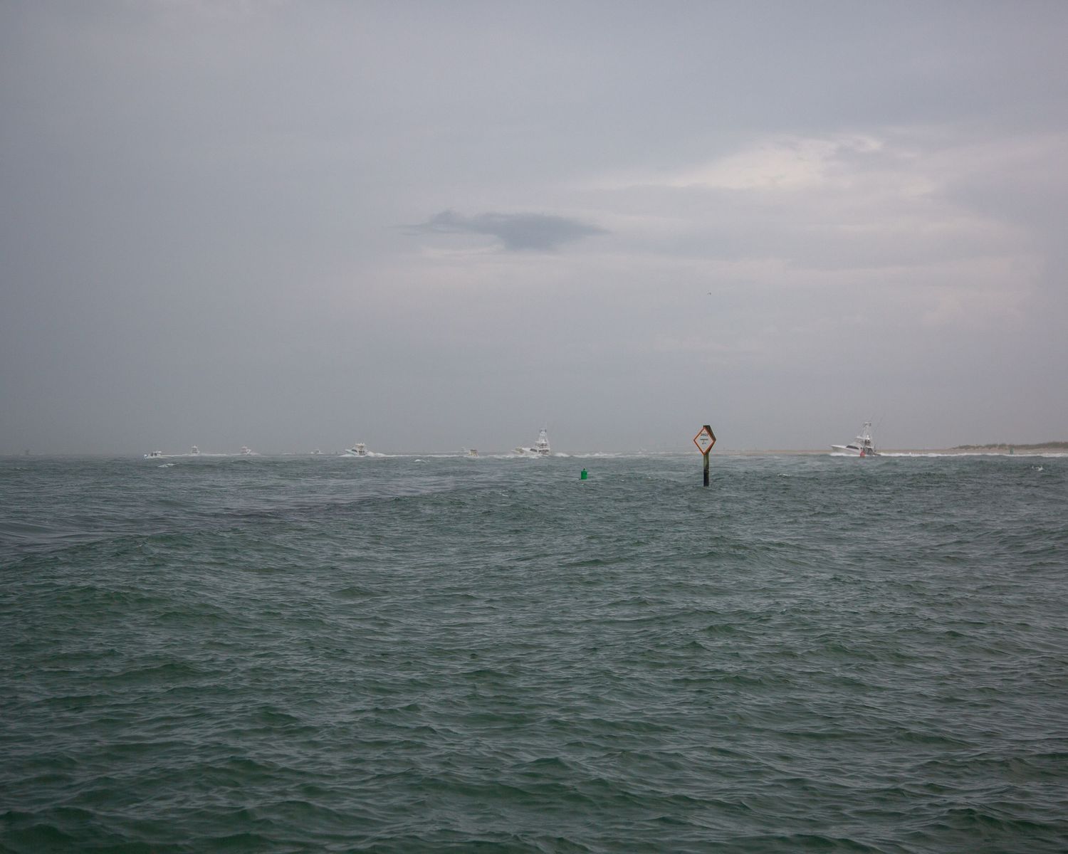 Navigation markers dot the choppy waters on an overcast day at sea.