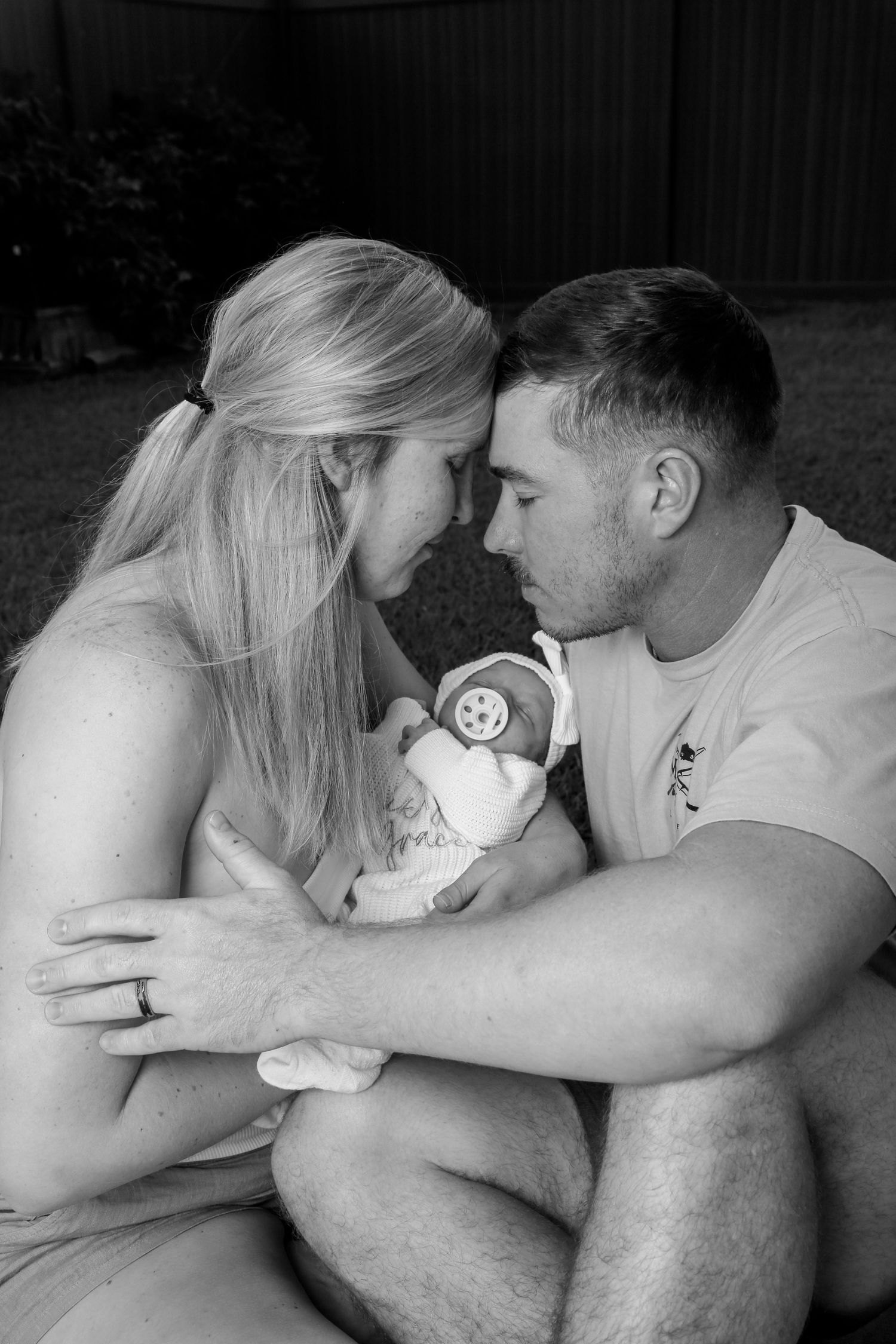 A couple shares an intimate black and white moment while holding a baby sonogram picture.