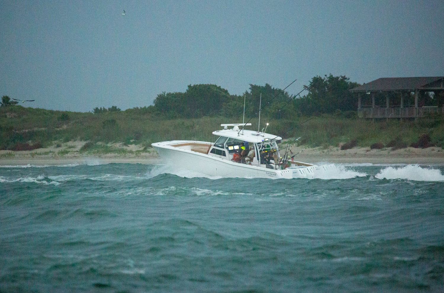 Fishing boats traverse choppy waters near a coastal shoreline.