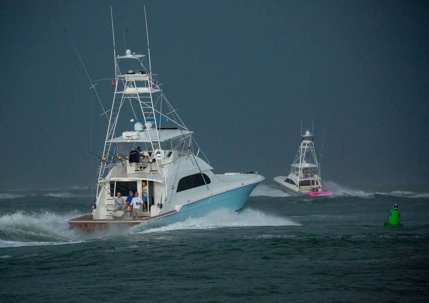 Sport fishing vessels power through choppy ocean waters near navigation markers.