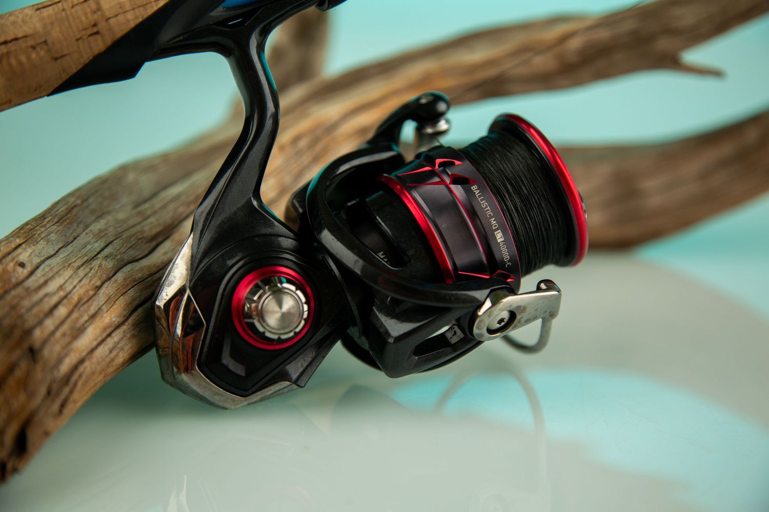 Close-up of black fishing reels mounted on display against turquoise background.