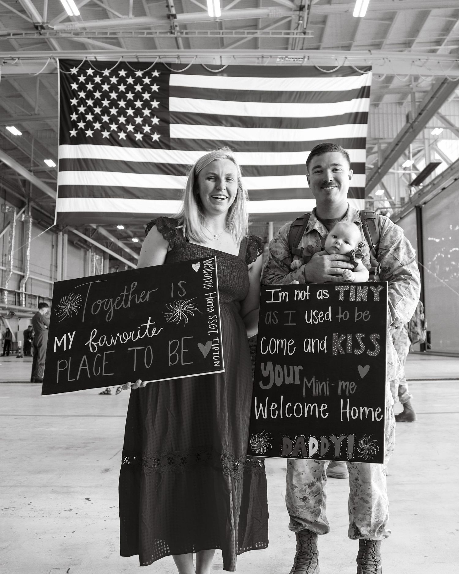Five black and white photos showing welcome home signs and American flags during military homecoming celebrations.