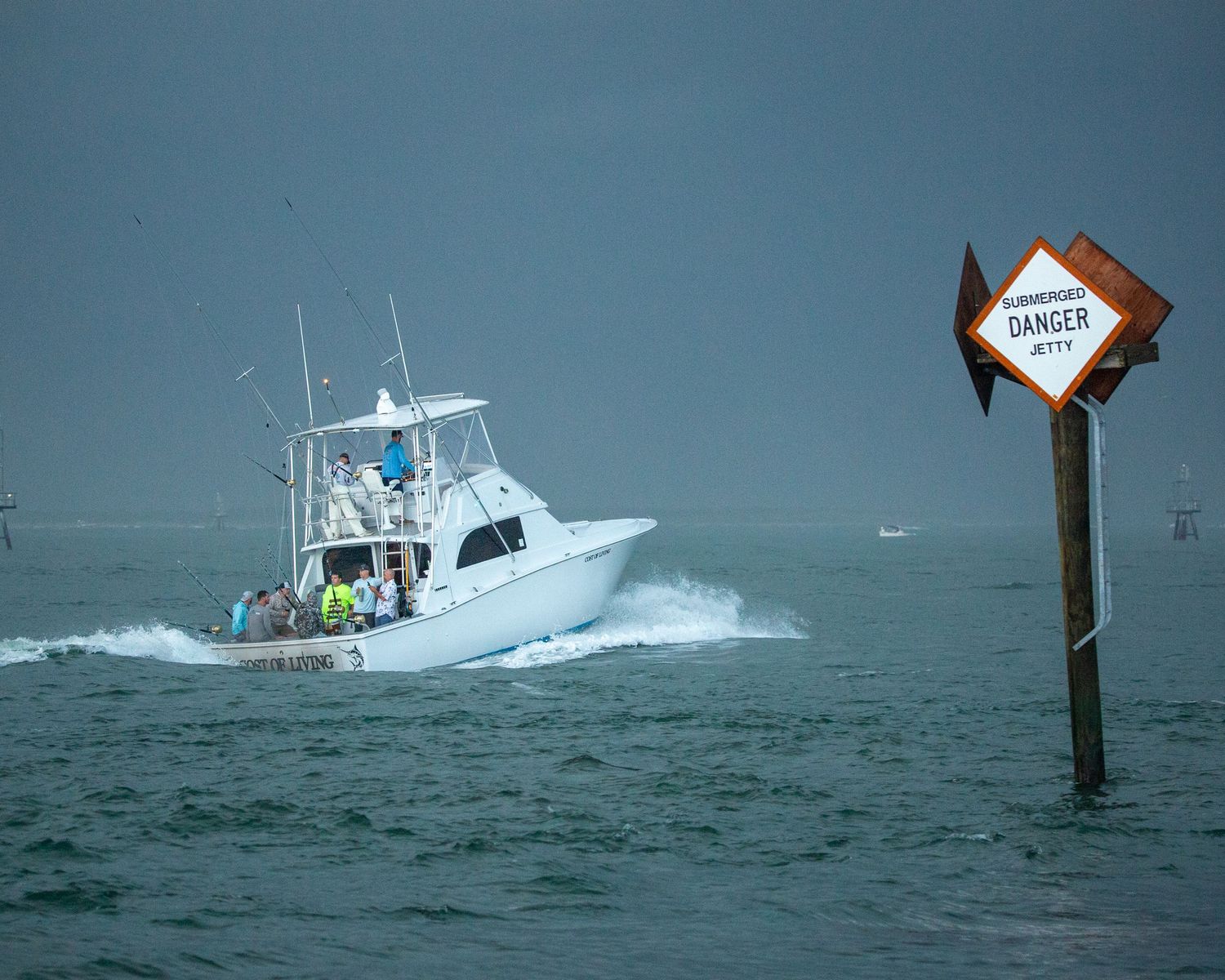 Sport fishing vessel powers through waves past a diamond-shaped warning marker.