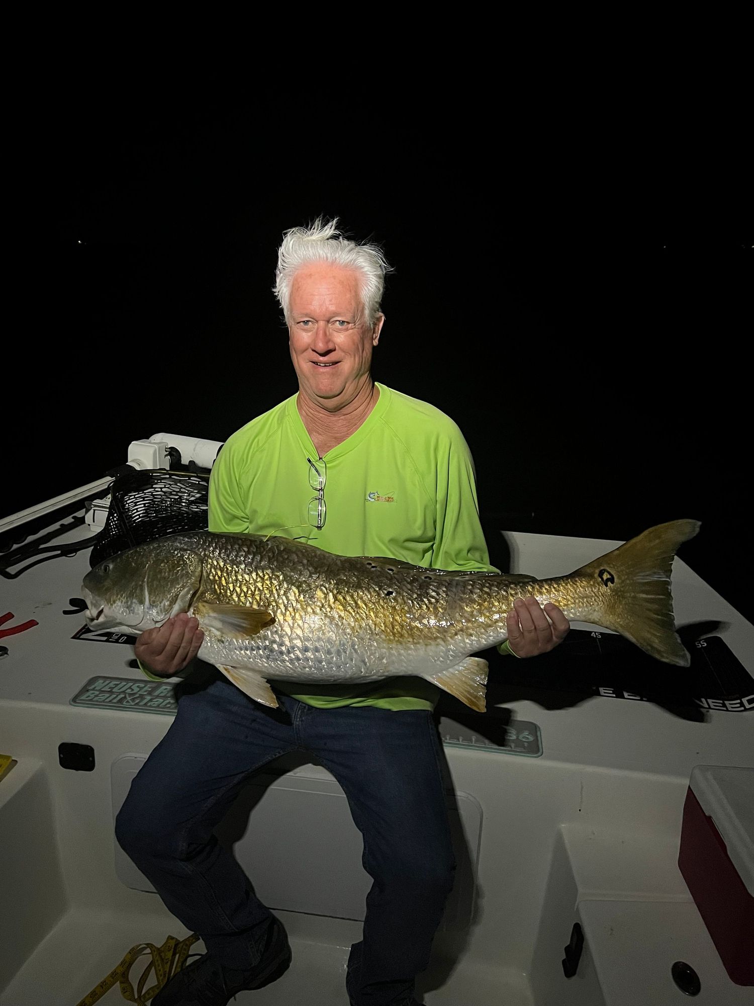 Large redfish catch being displayed on a boat during a nighttime fishing expedition.