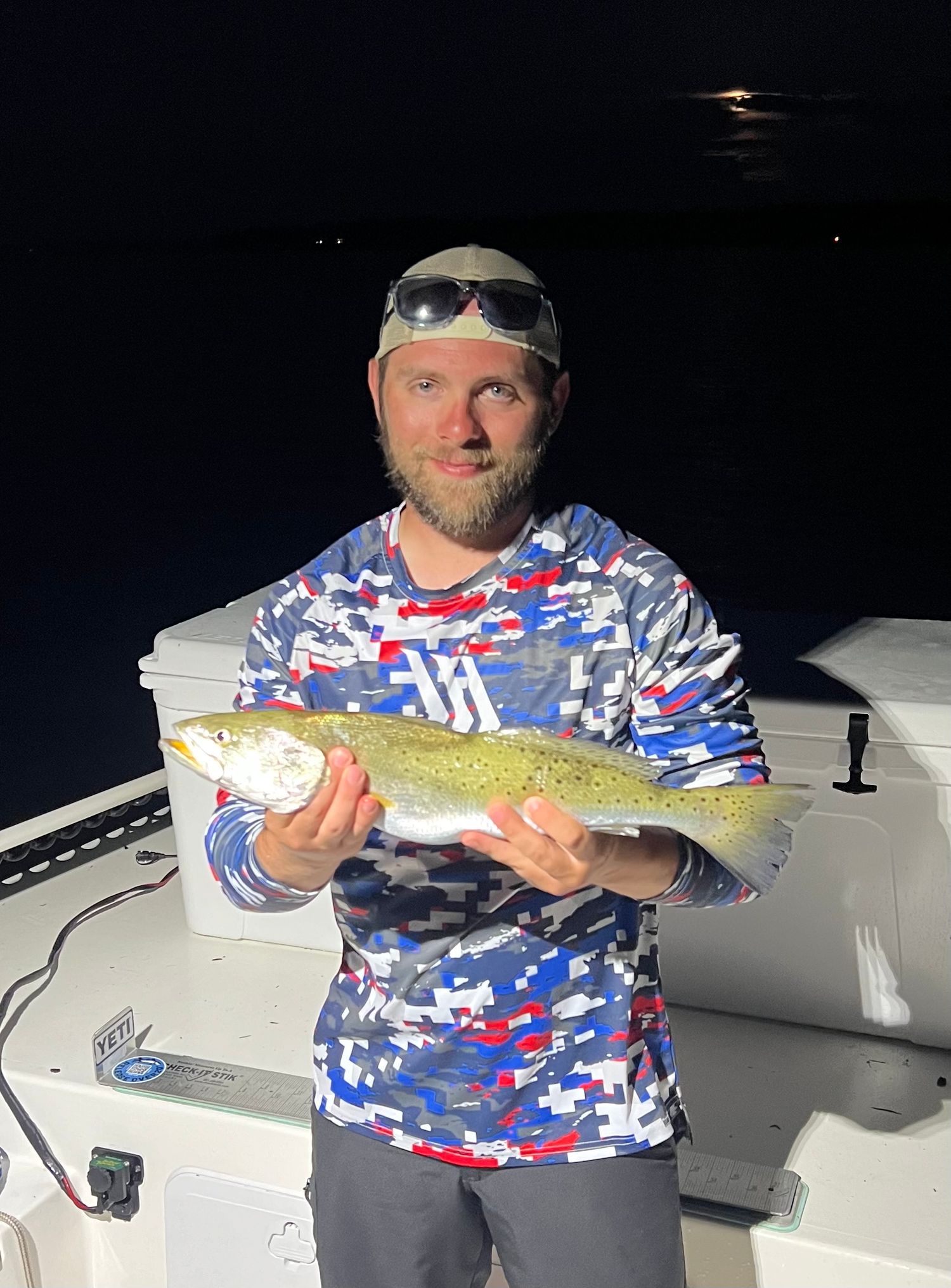 Night fishing success with redfish catch illuminated by moonlight on boat deck.