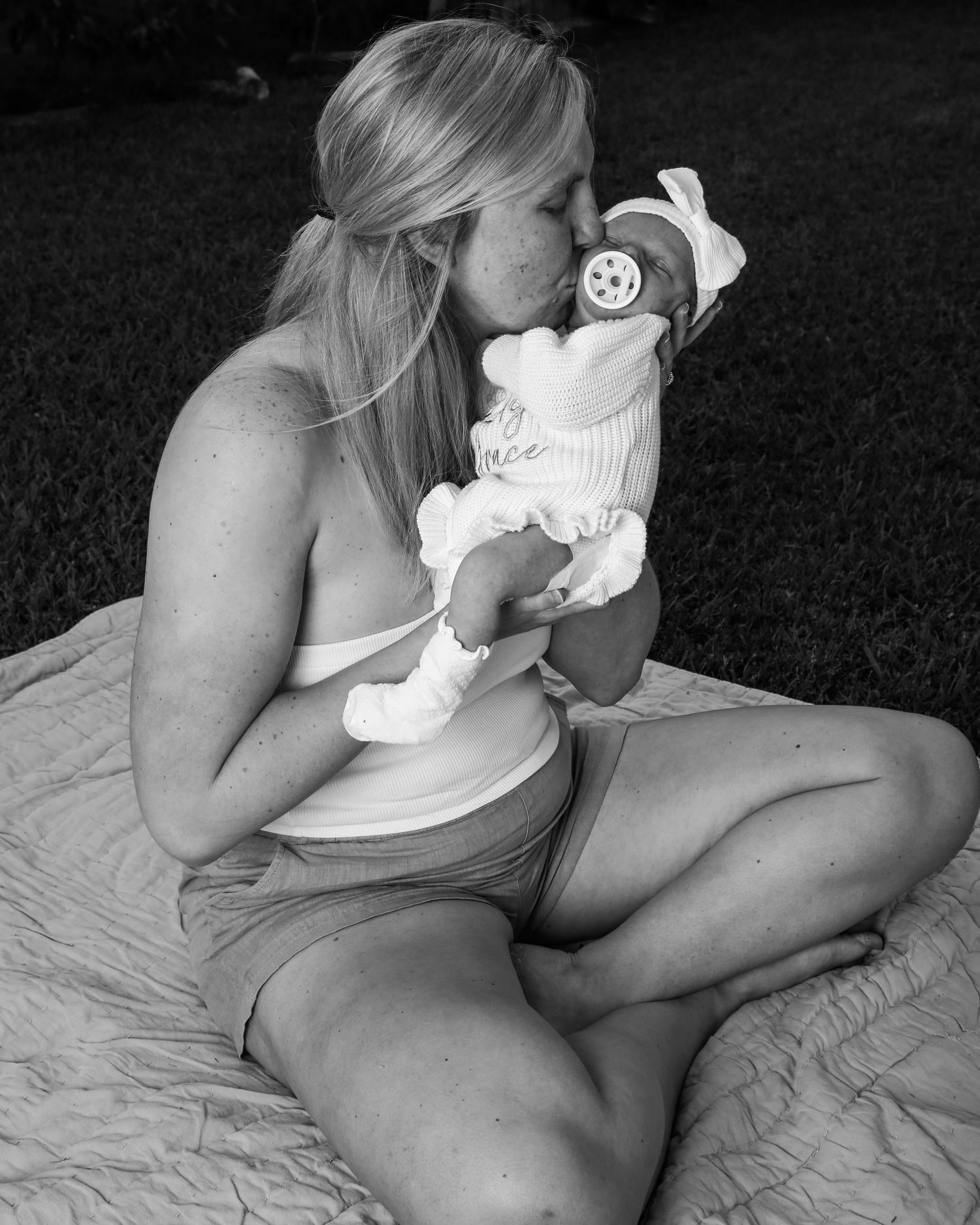 Black and white image sequence showing someone sitting on a blanket outdoors while holding a white plush toy.