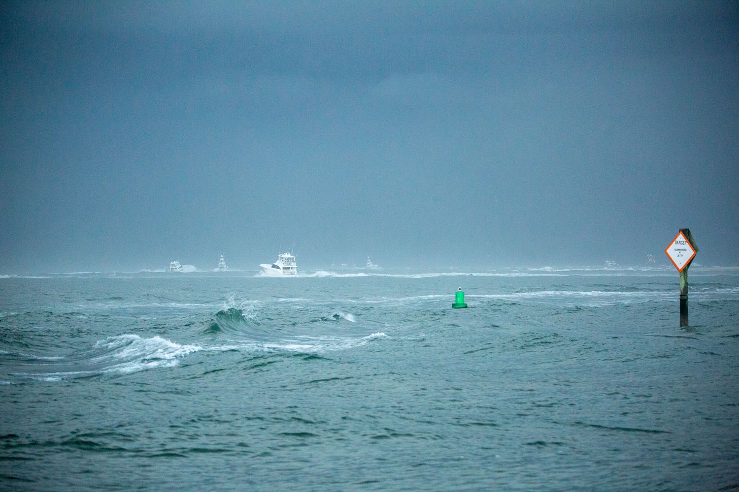 Fishing boats traverse rough waters with navigation markers visible in stormy conditions.