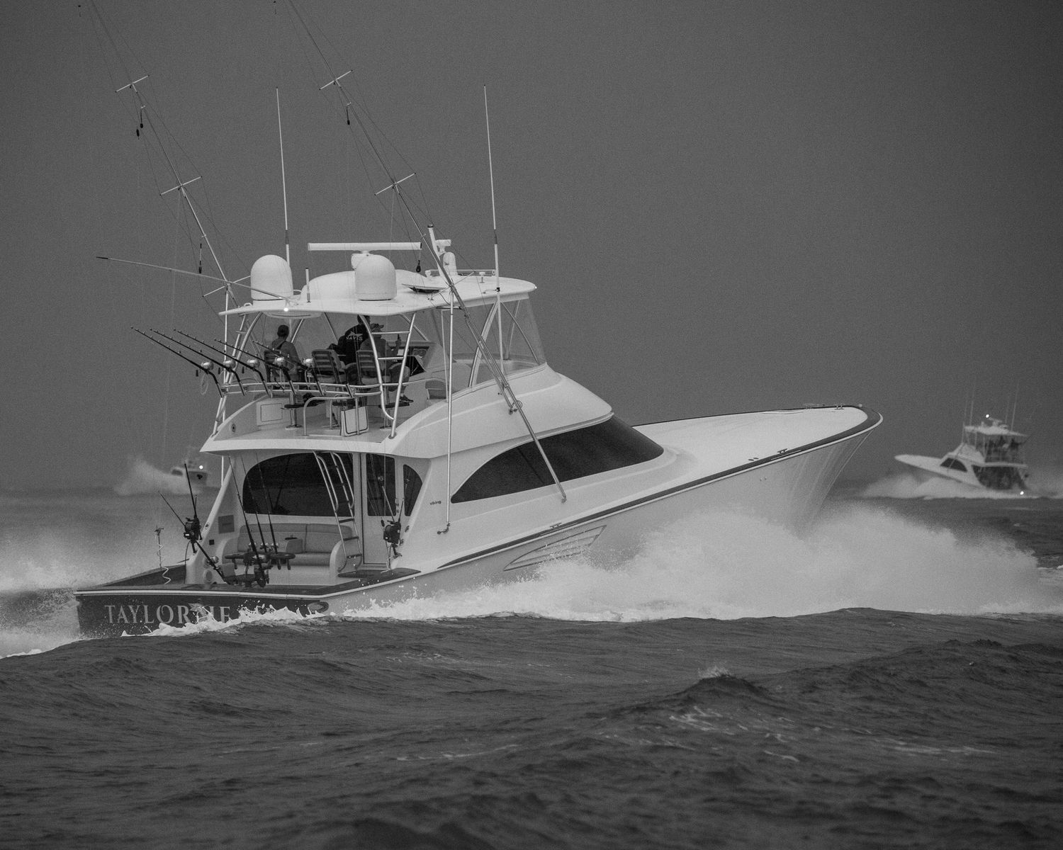 Black and white photo of a luxury sportfishing yacht creating wake while cruising at high speed.