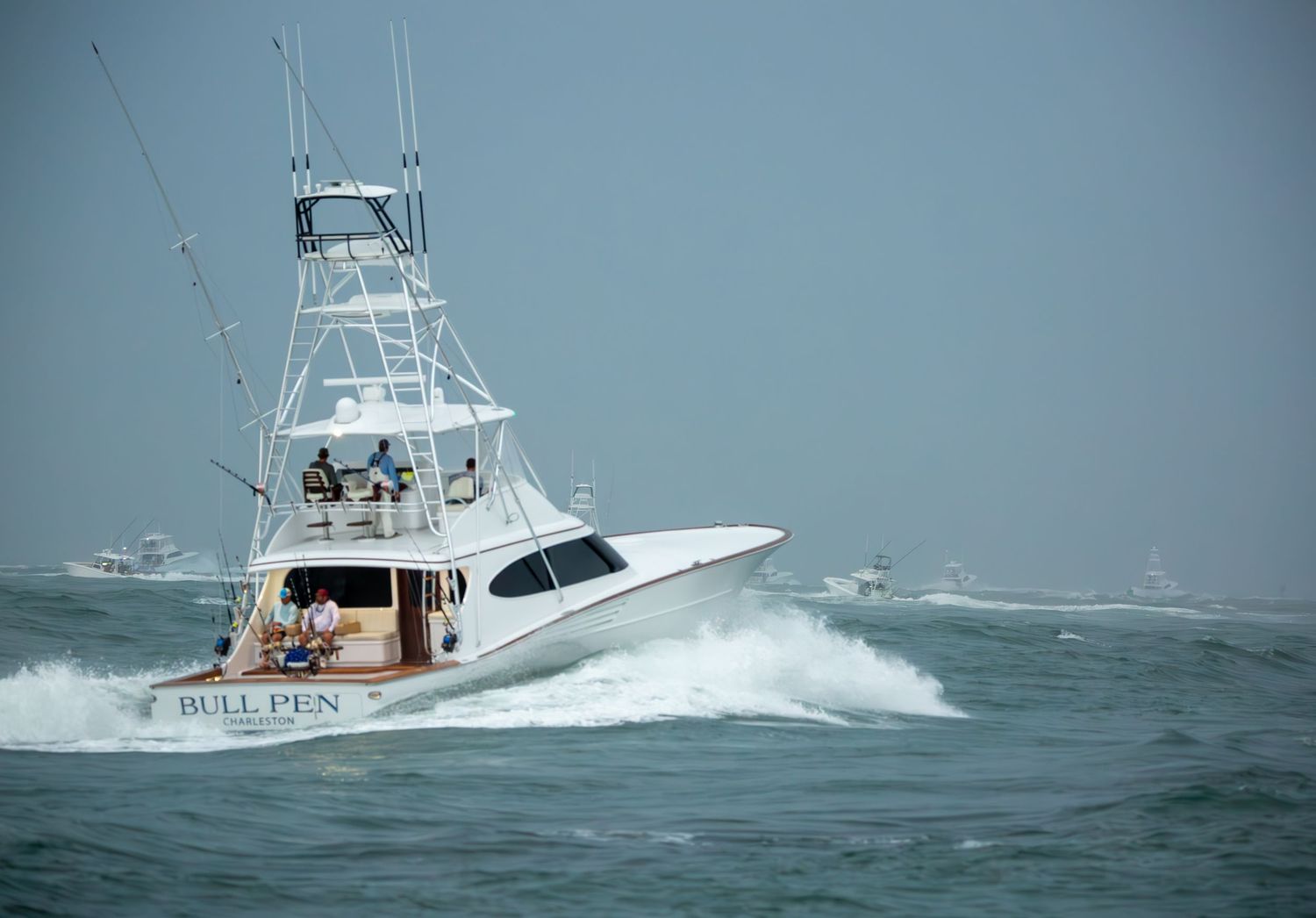 White sport fishing boat creating large wake while speeding through rough waters.