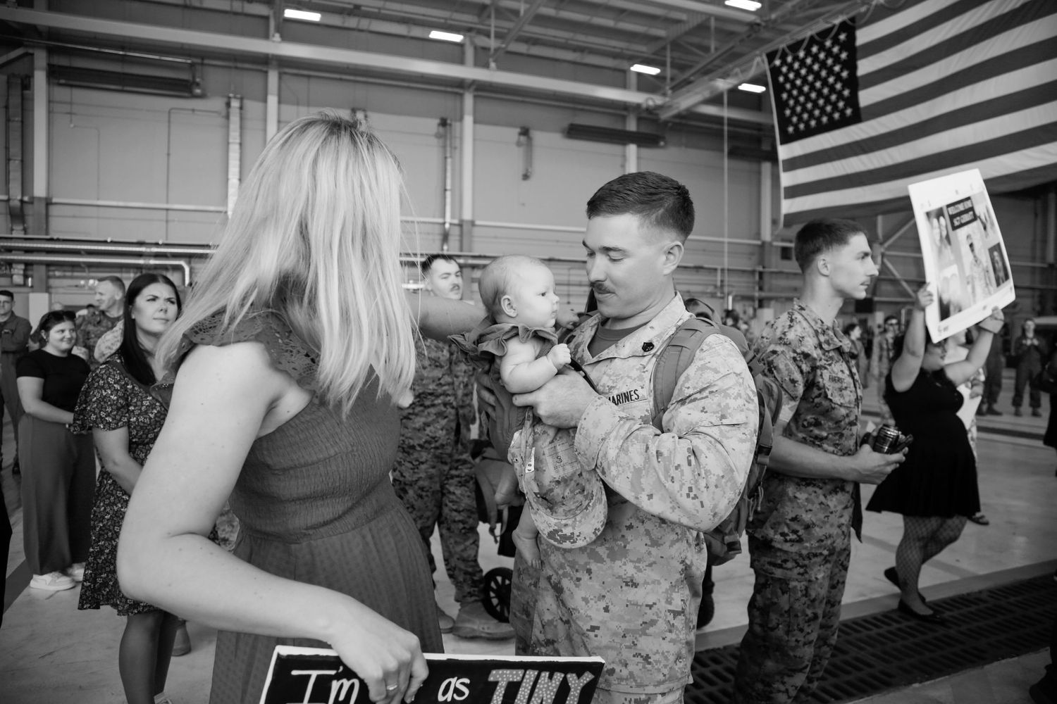 Military homecoming celebration with American flags displayed in an indoor facility.