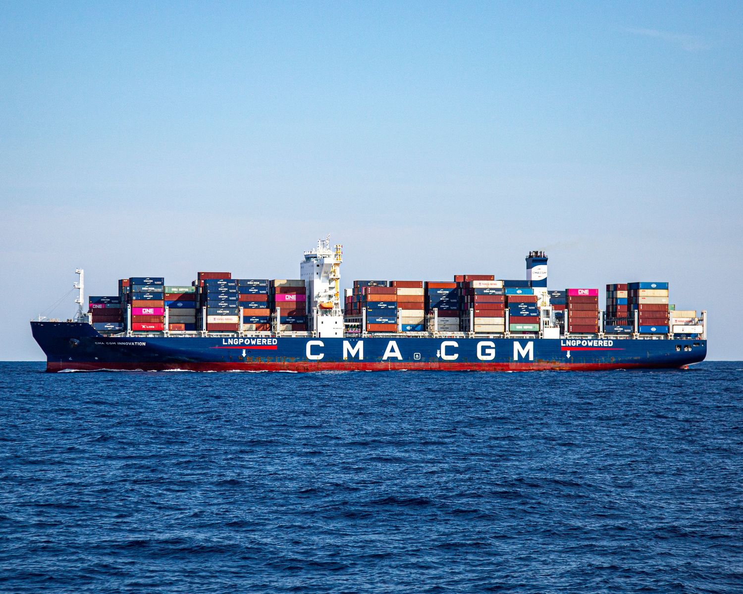 CMA CGM cargo container ship loaded with colorful shipping containers sailing on calm blue ocean waters.