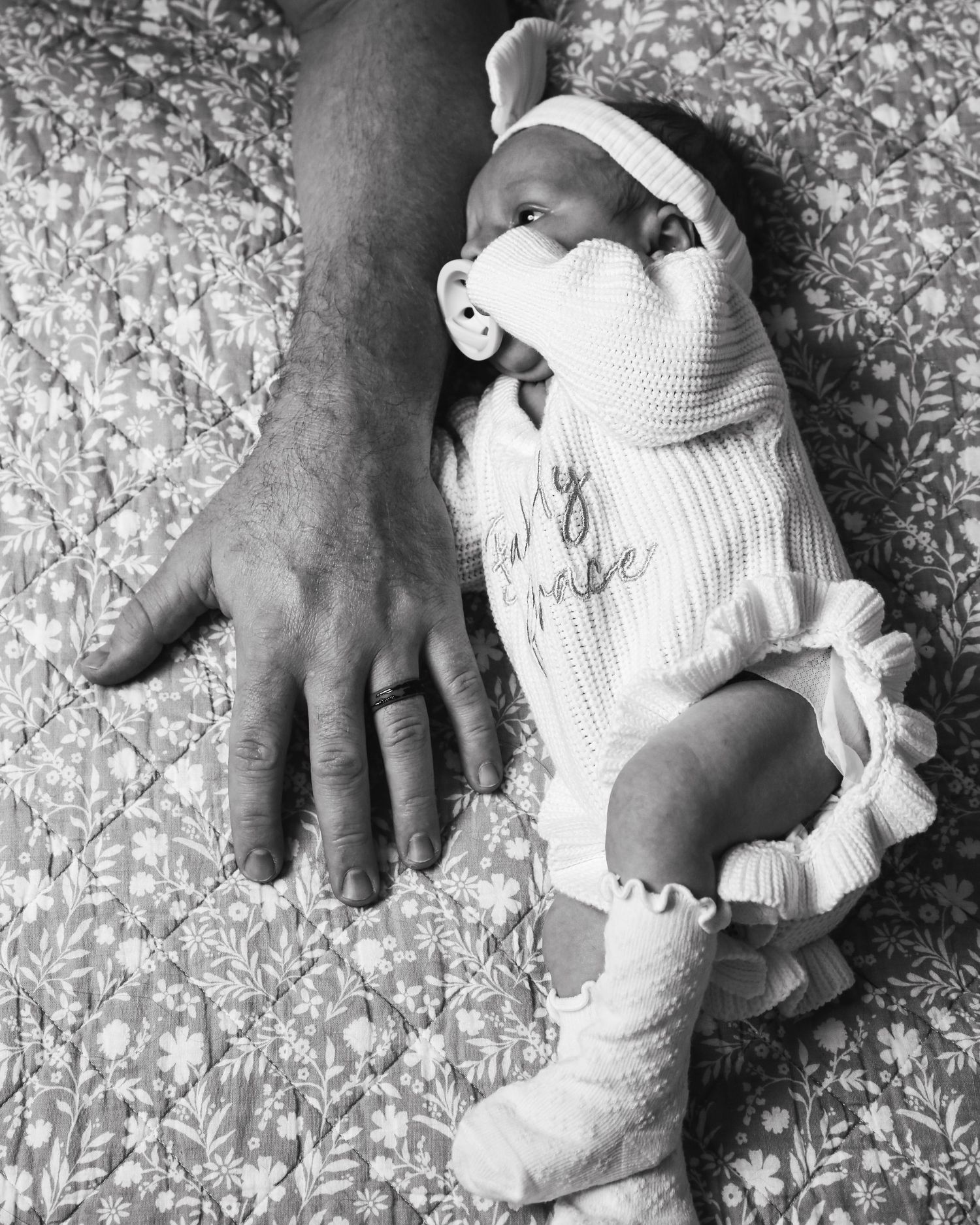 Black and white photo series showing small hands grasping a soft white stuffed toy against a patterned background.