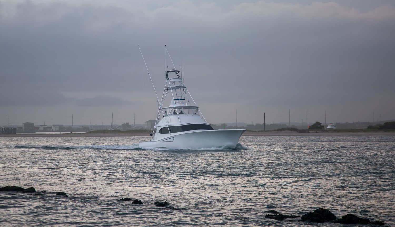 Sport fishing boat sailing through choppy waters under dramatic storm clouds.