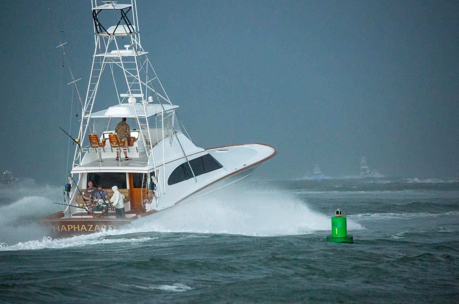 Fishing vessels navigate channel markers while battling rough waters.