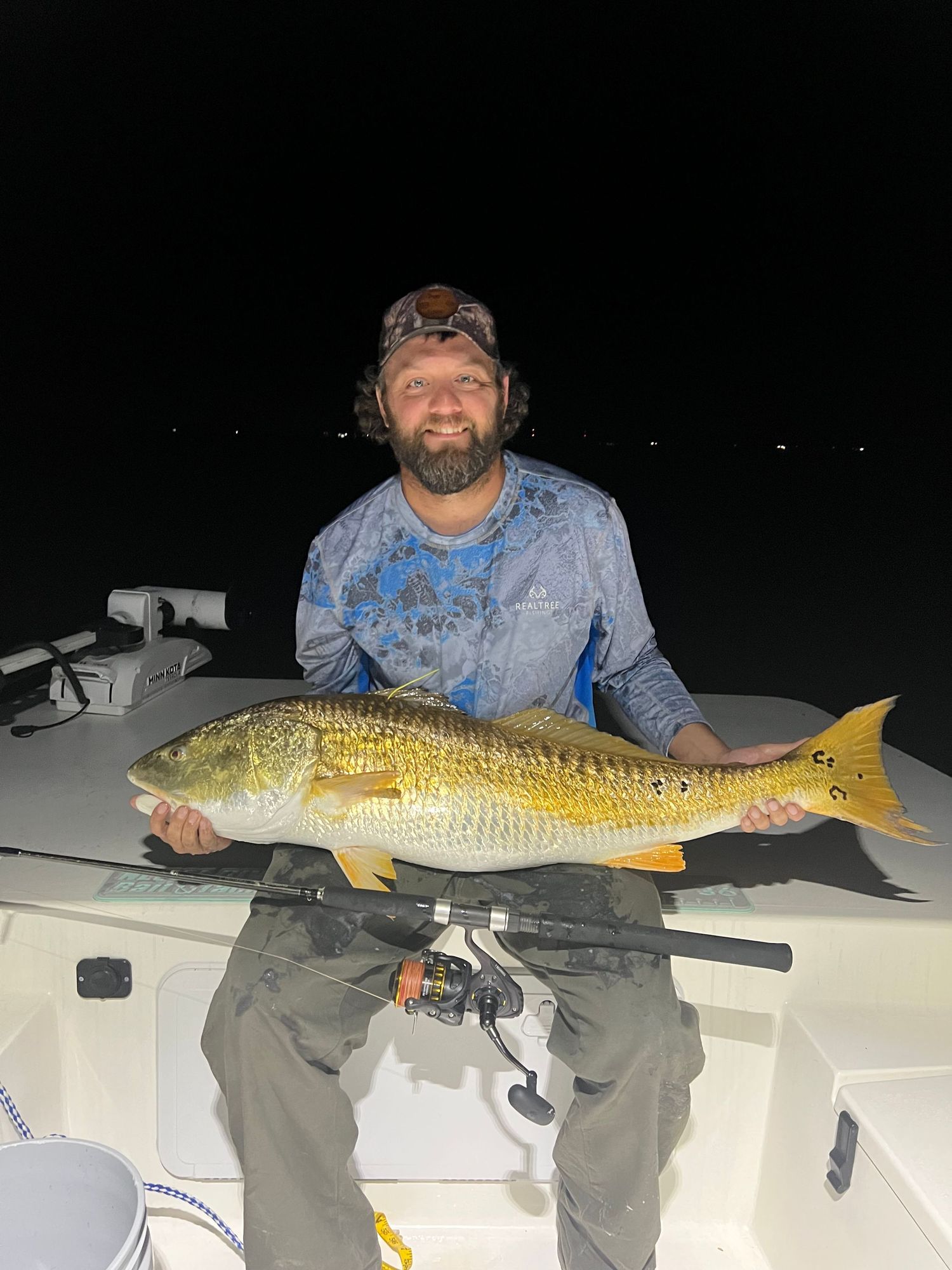 Large golden redfish displayed on boat deck during nighttime fishing.