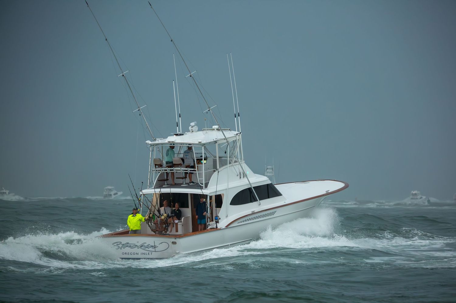 Sport fishing yacht rides through stormy seas with large waves crashing against hull.