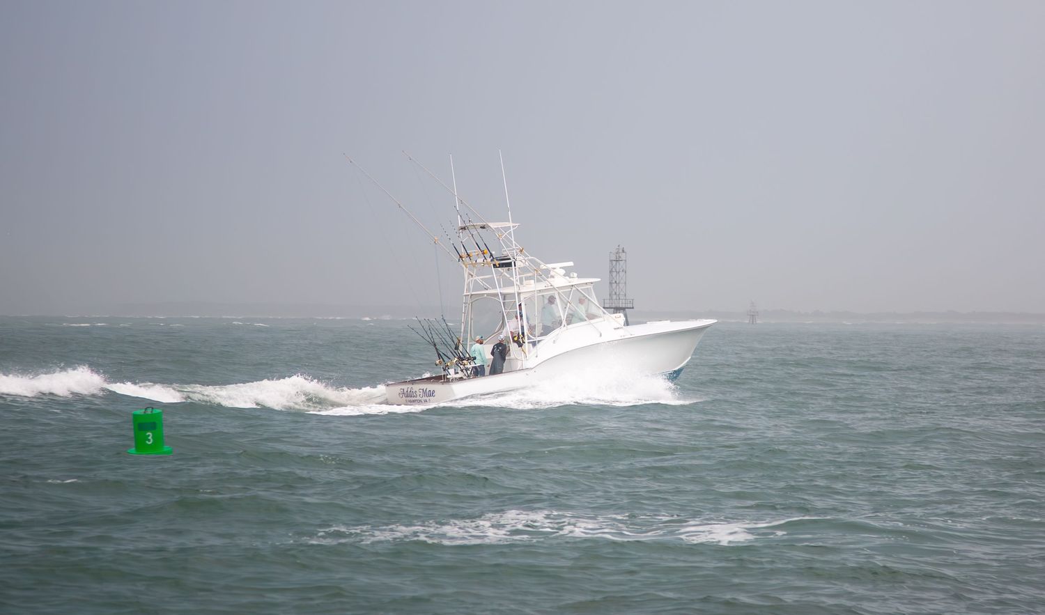 Sport fishing vessel navigating rough seas with visible green navigation marker.