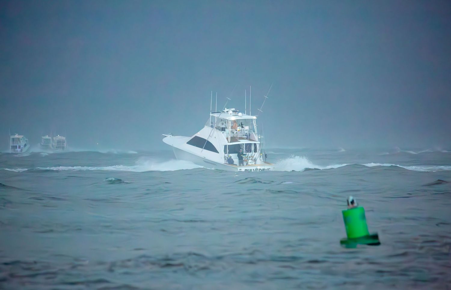 Sport fishing boat battling rough seas near a green channel marker buoy.