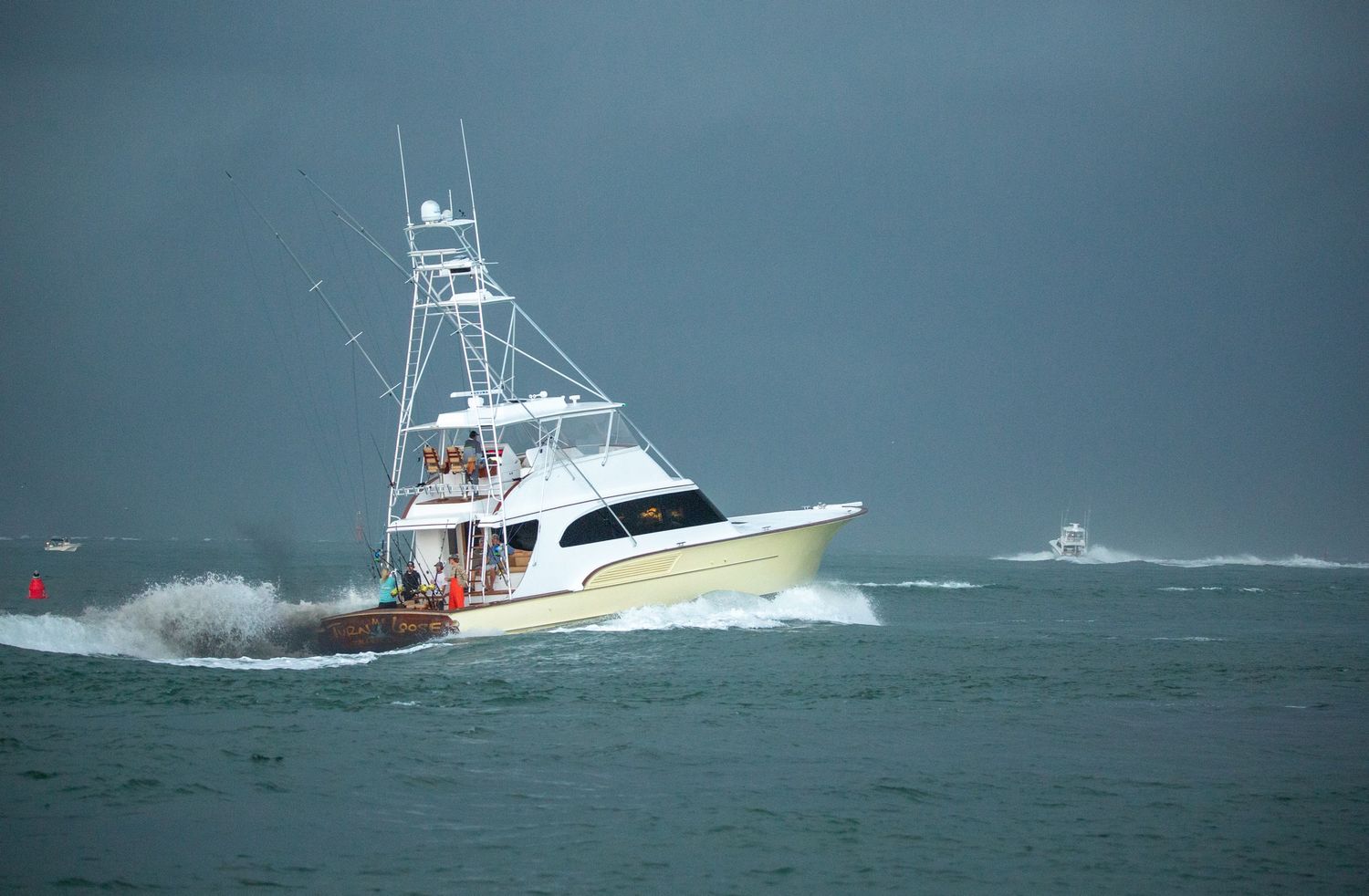 White sport fishing boat cutting through stormy seas with waves crashing against its hull.