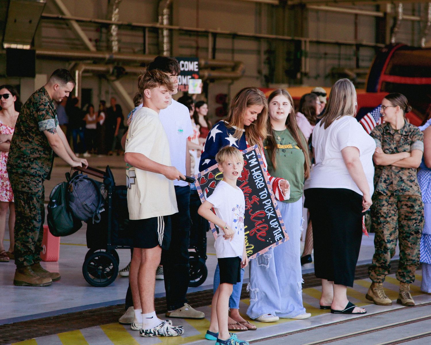 A line of people wait along a wall in what appears to be a military recruitment or processing center.