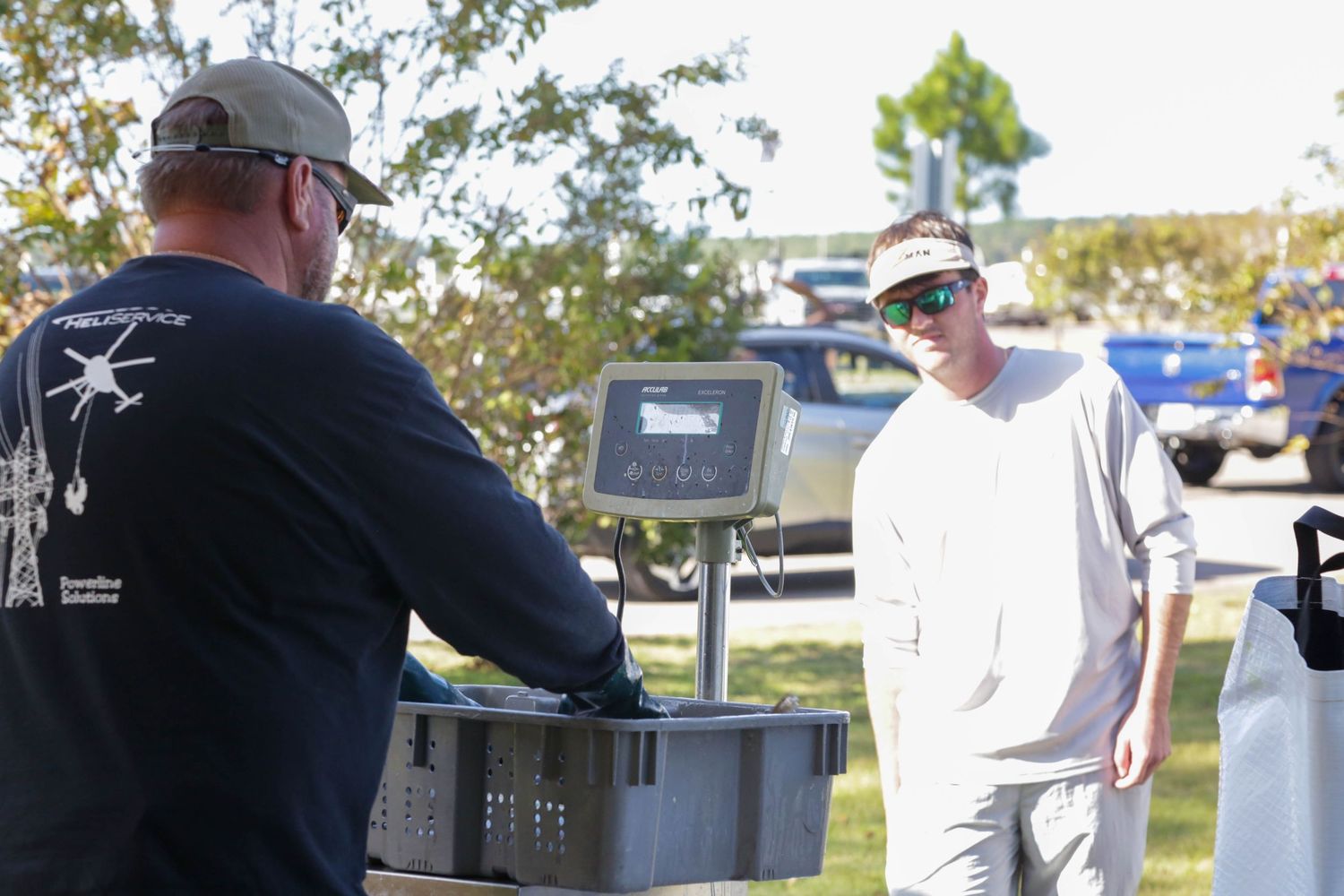Two people discussing equipment at outdoor fishing event display.