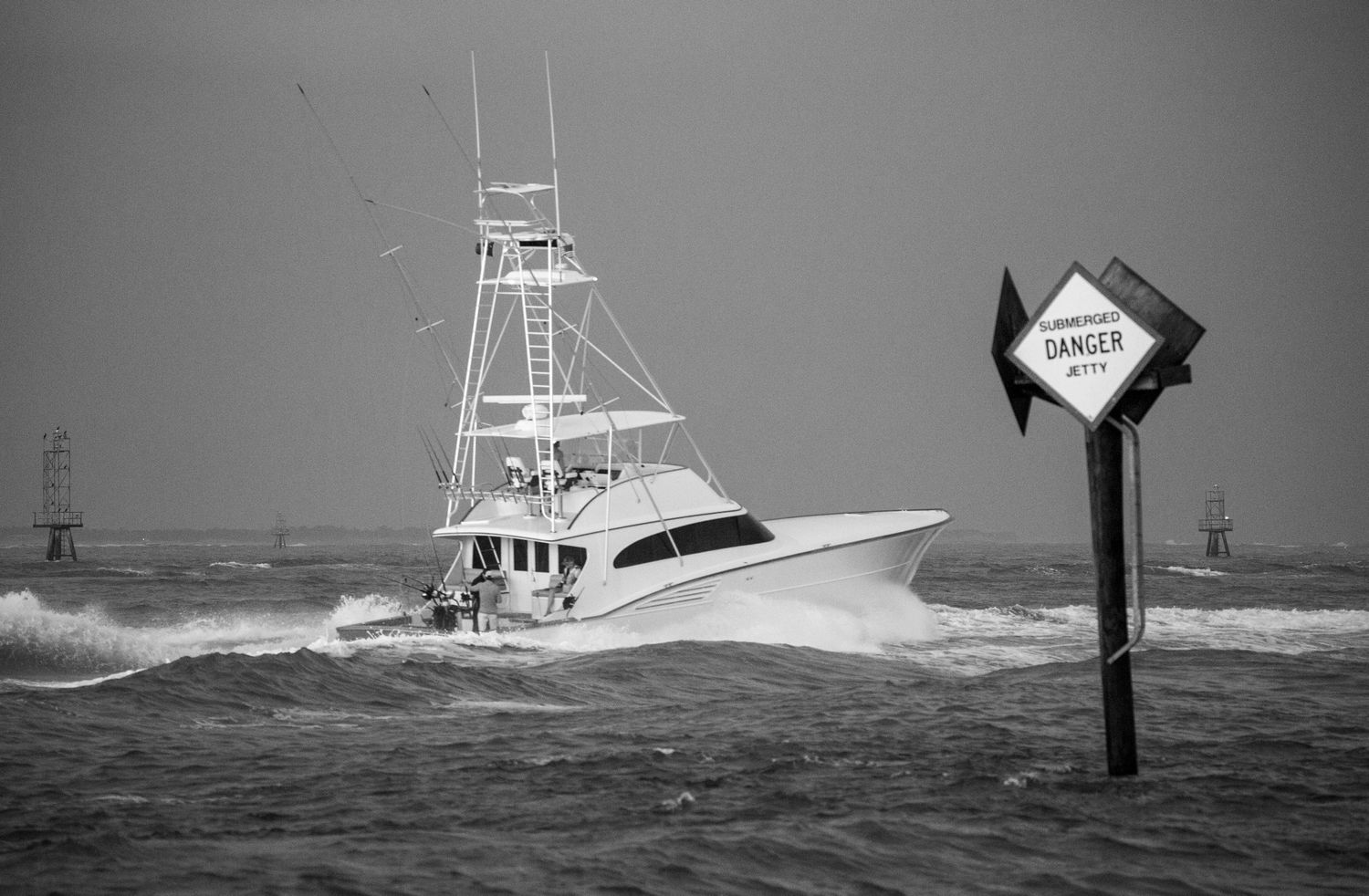 Multiple fishing vessels navigate rough seas with warning signs visible in black and white.