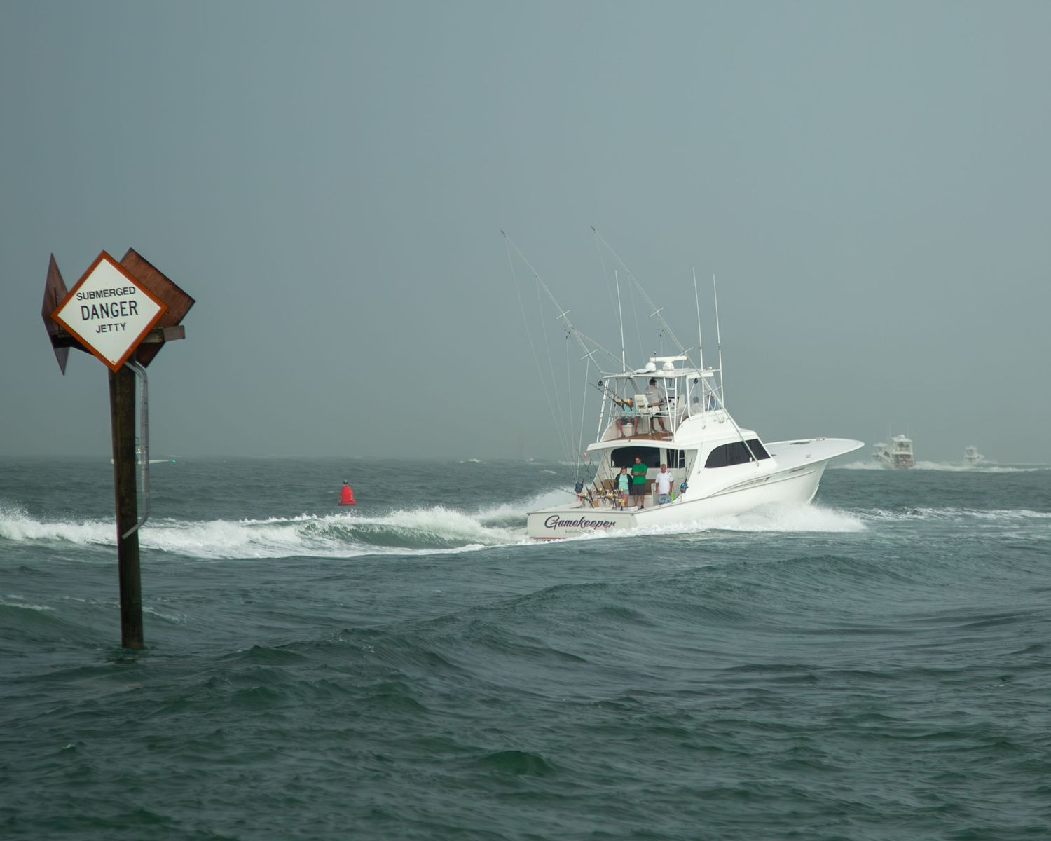 A fishing boat navigates through rough ocean waves in stormy conditions.